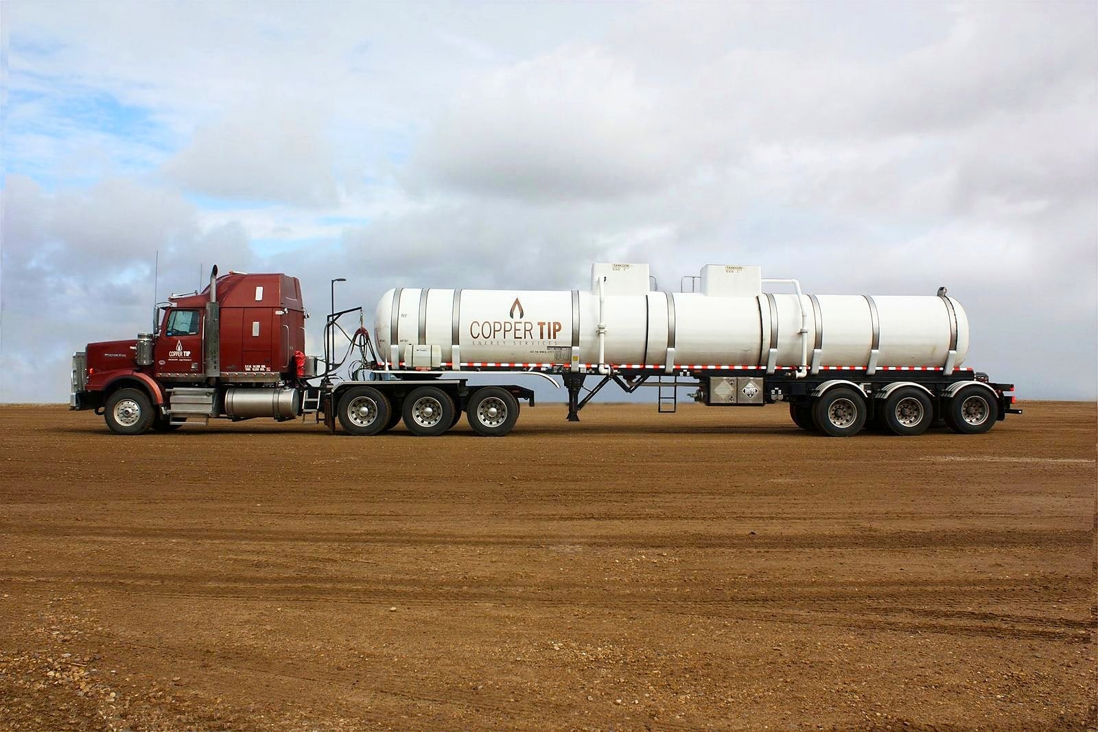 Copper Tip Energy Services acid bulk trailer and tractor on a gravel lease