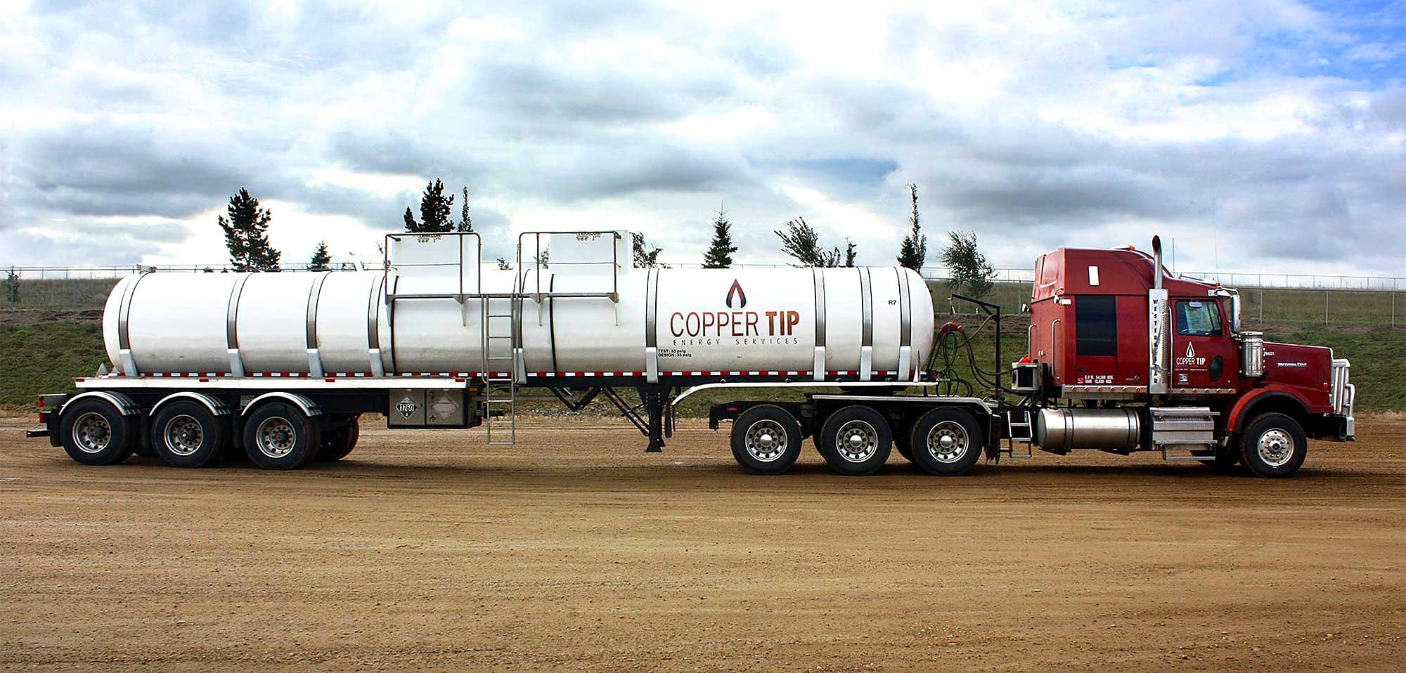 Copper Tip Energy Services acid transport trailer on gravel road